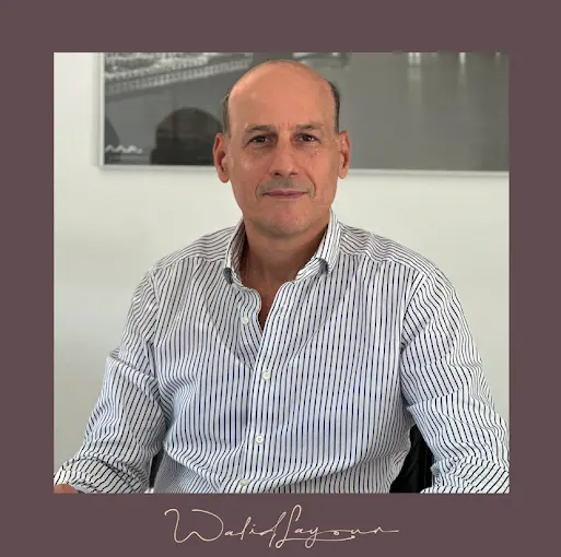 le dr layoun chirurgien maxillo facial Aix en Provence Homme avec lunettes, chemise bleue, pense.