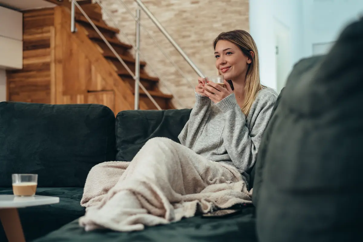 suites opératoires et récupération après une profiloplastie Nice Femme sur canapé buvant boisson chaude